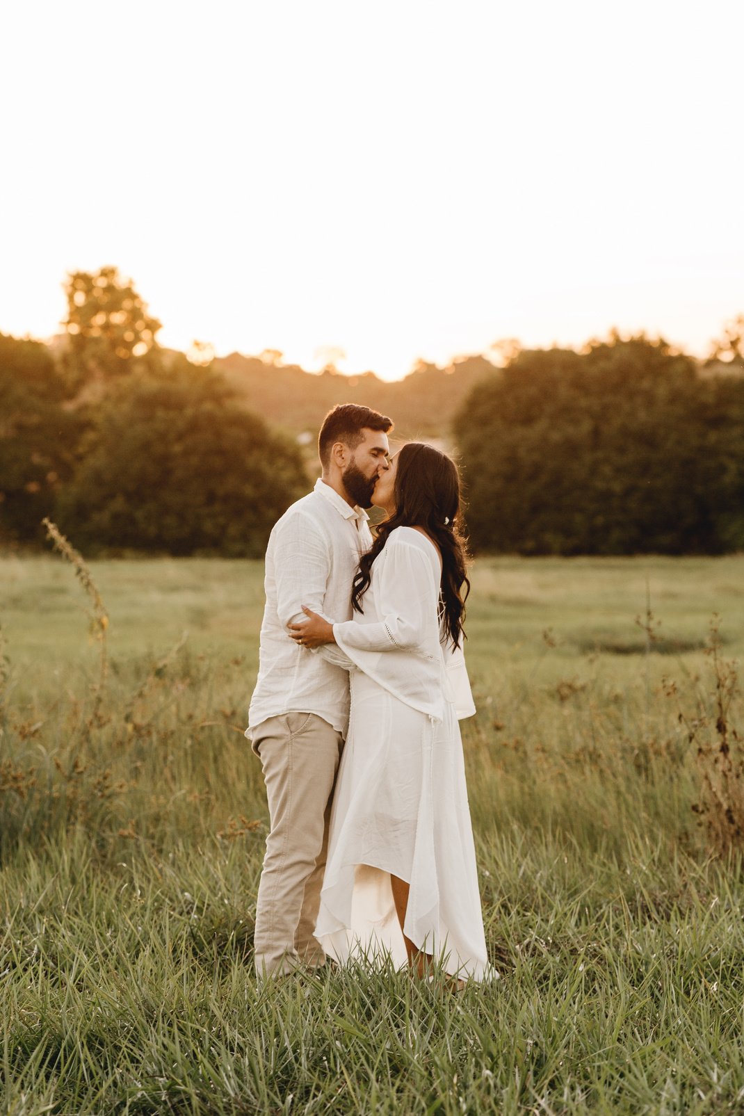 Loving couple embracing in meadow at sunset