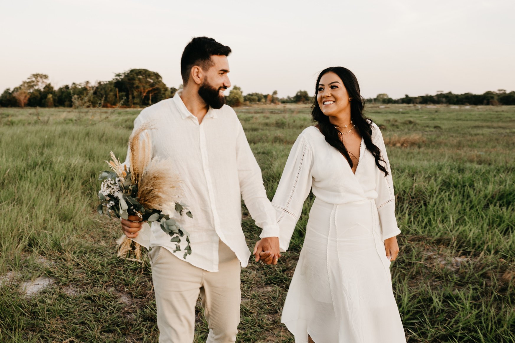 Happy couple holding hands while walking in meadow